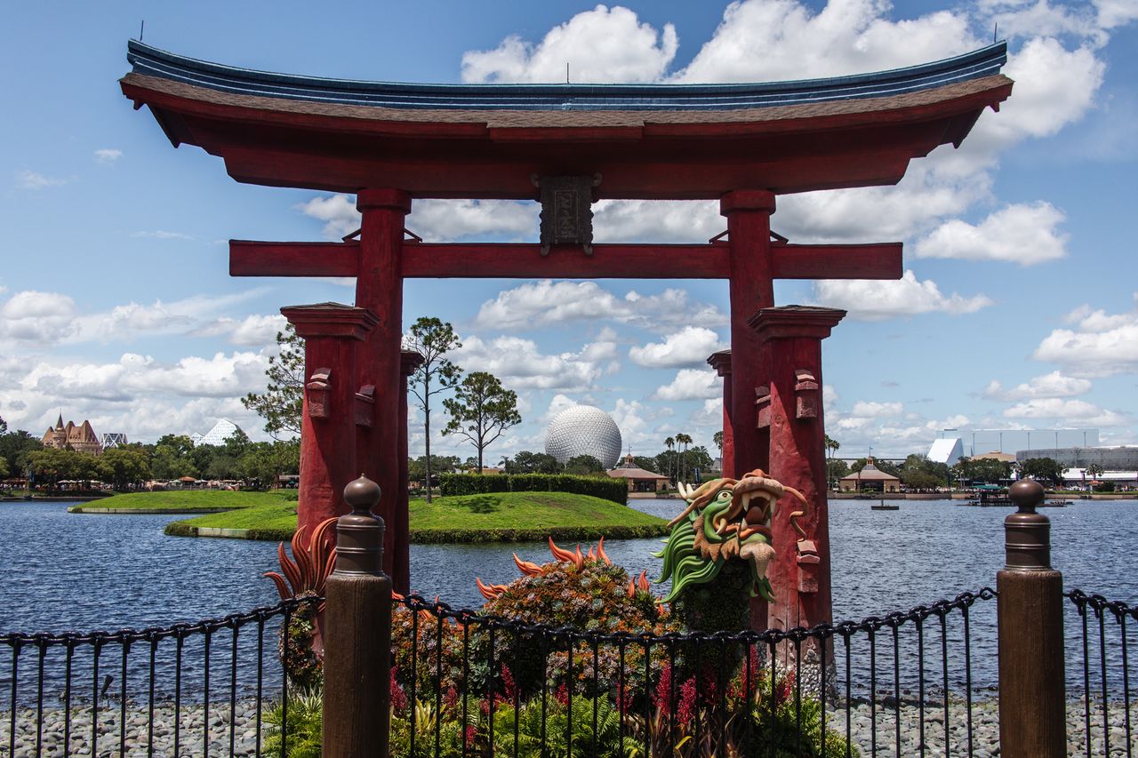 Torii gate with Epcots Spaceship Earth visible in the background across a water pond
