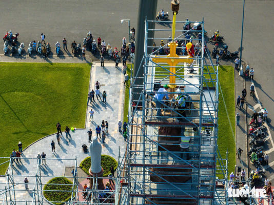 Rất đông người dân theo dõi quá trình lắp đặt thánh giá phía ngoài nhà thờ - Ảnh: VĂN TRUNG