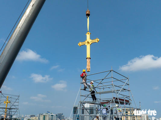 Đưa hai cây thánh giá lên đỉnh tháp kẽm nhà thờ chính tòa Đức Bà Sài Gòn - Ảnh: VĂN TRUNG