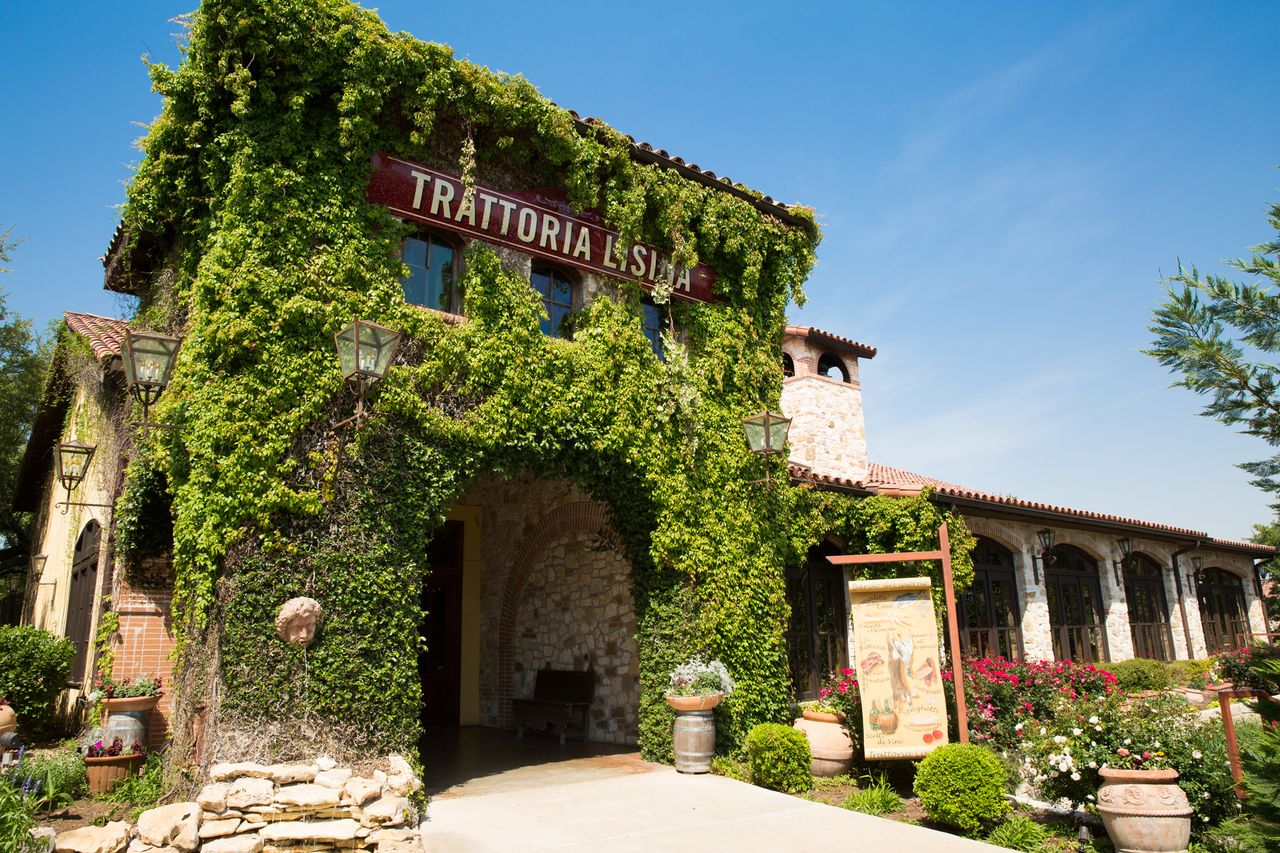 Exterior view of Trattoria Lisina showing an ivycovered building with archways and signage