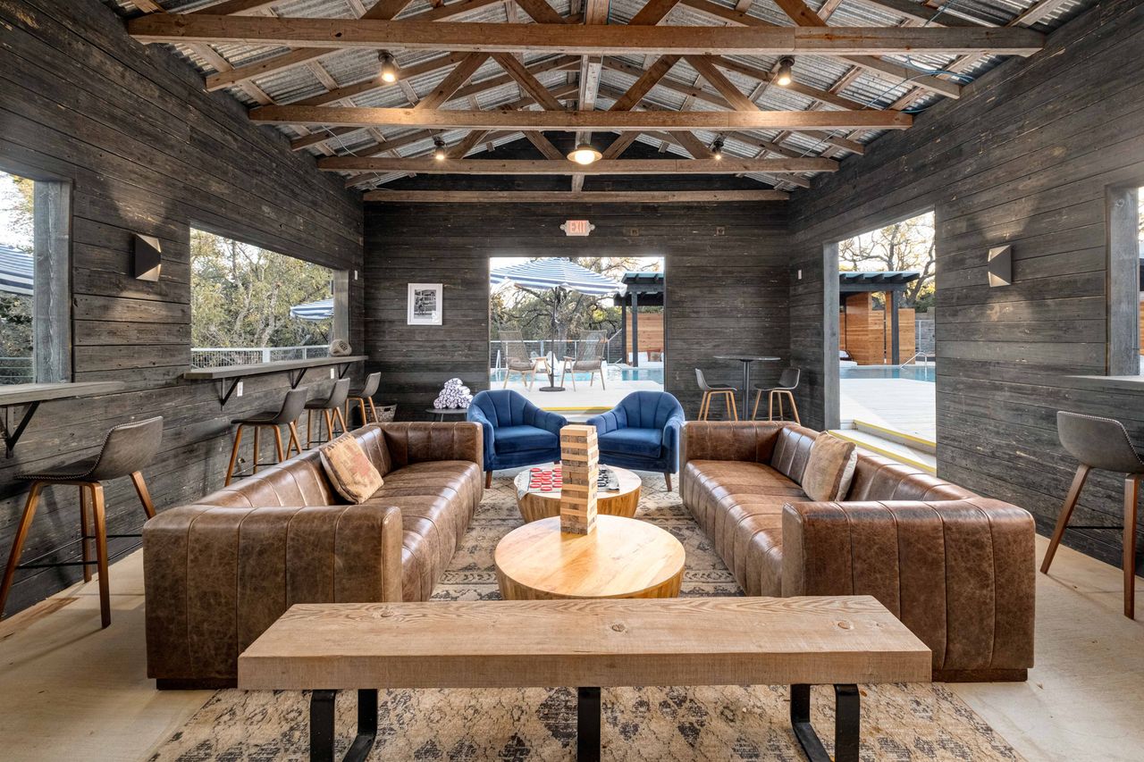 A cozy lounge space with brown leather seating blue armchairs a wooden coffee table and a stack of Jenga blocks featuring a rustic wood interior
