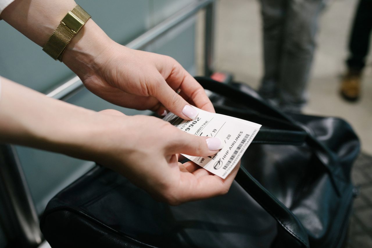 A person holding a travel pass near a bag airport scenario