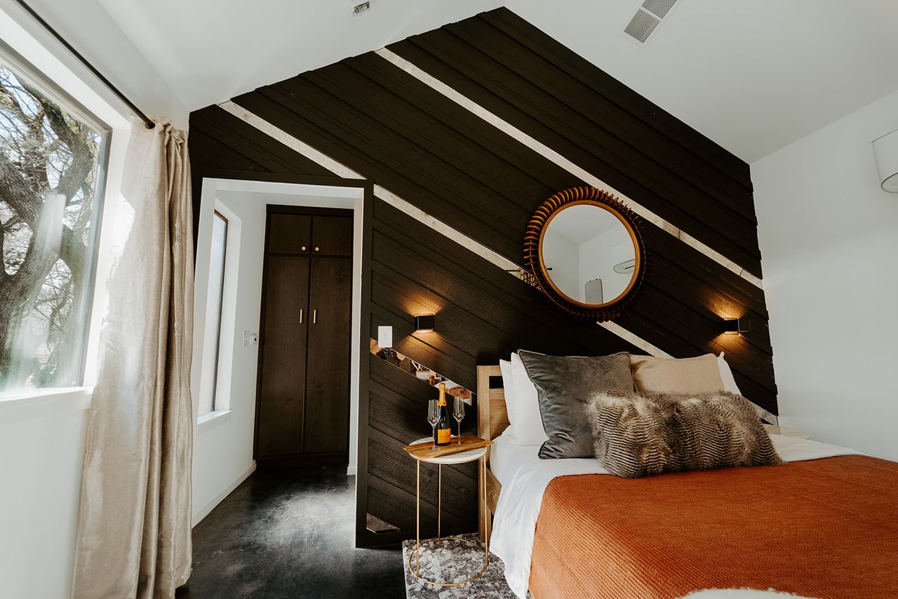 Interior of a cabin bedroom with a bed side table and diagonal wall paneling