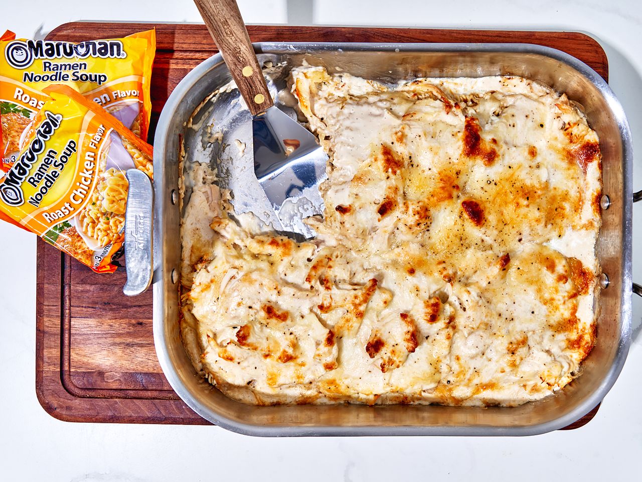 overhead view of ramen chicken Alfredo casserole with ramen packets and spatula