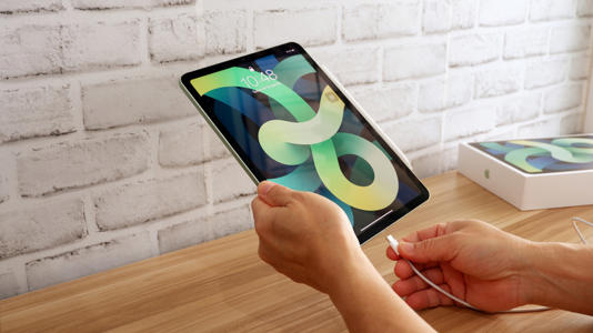 A person about to plug in the charging cable of an iPad.