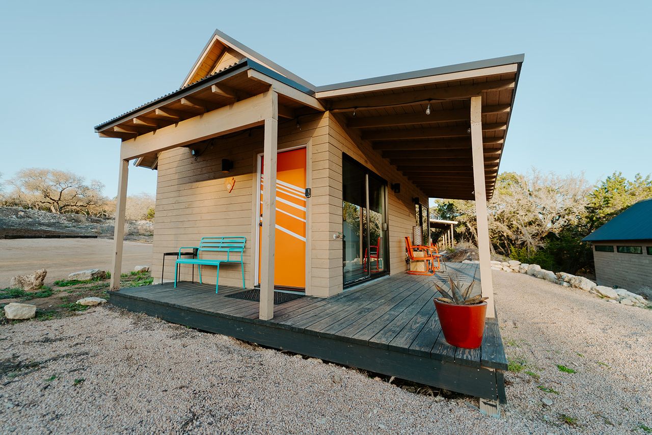 A retreat cabin with a wooden porch located in a rural setting with scattered vegetation