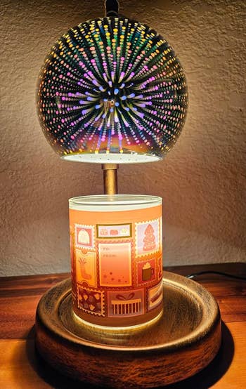 Decorative lamp with a glowing, dotted sphere on top of a candleholder featuring gift-themed designs