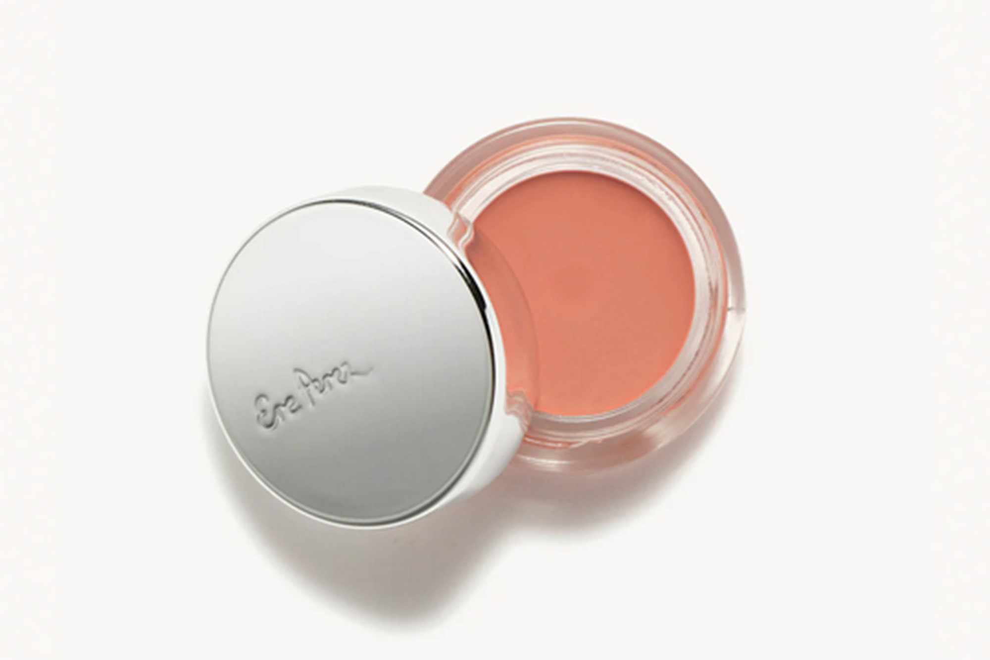Open pot of peach-colored cream blush with a silver lid that reads 