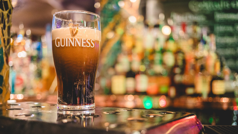 Pint of Guinness settling before the second pour with pub interior blurred in background