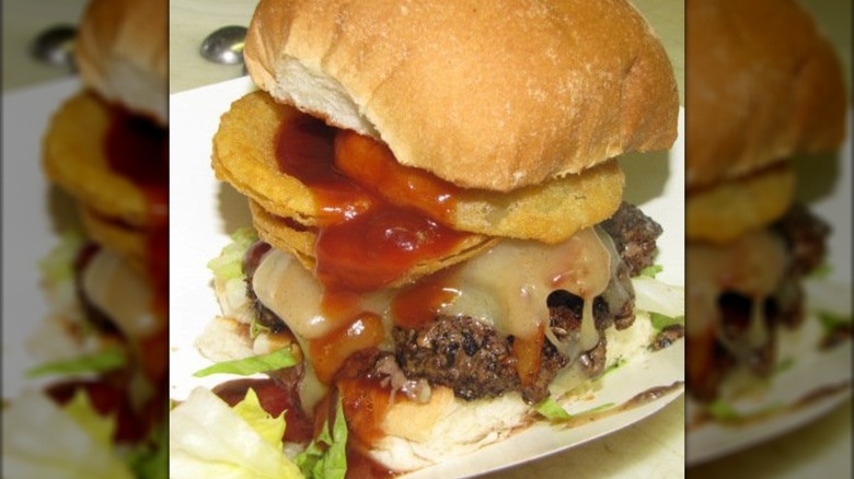 Burger with cheese, lettuce, and onion rings