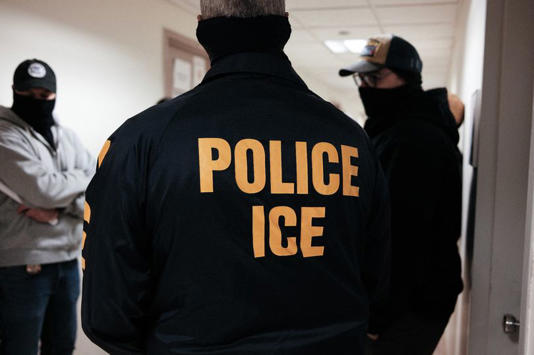 Masked federal agents wearing a Police ICE jacket, stand in a hallway at the New York Federal Plaza Immigration Court inside the Jacob K. Javitz Federal Building in New York on March 17, 2026. US President Donald Trump has made deporting undocumented immigrants a key priority for his second term, after successfully campaigning against an alleged 