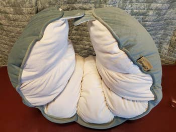 Plush white and green body pillow shaped like a pea pod, shown on a quilting backdrop