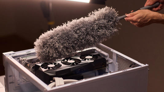A gaming PC being cleaned by a brush.