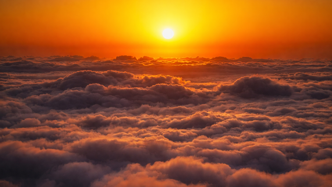 The sun rising gently over a quiet cloud landscape