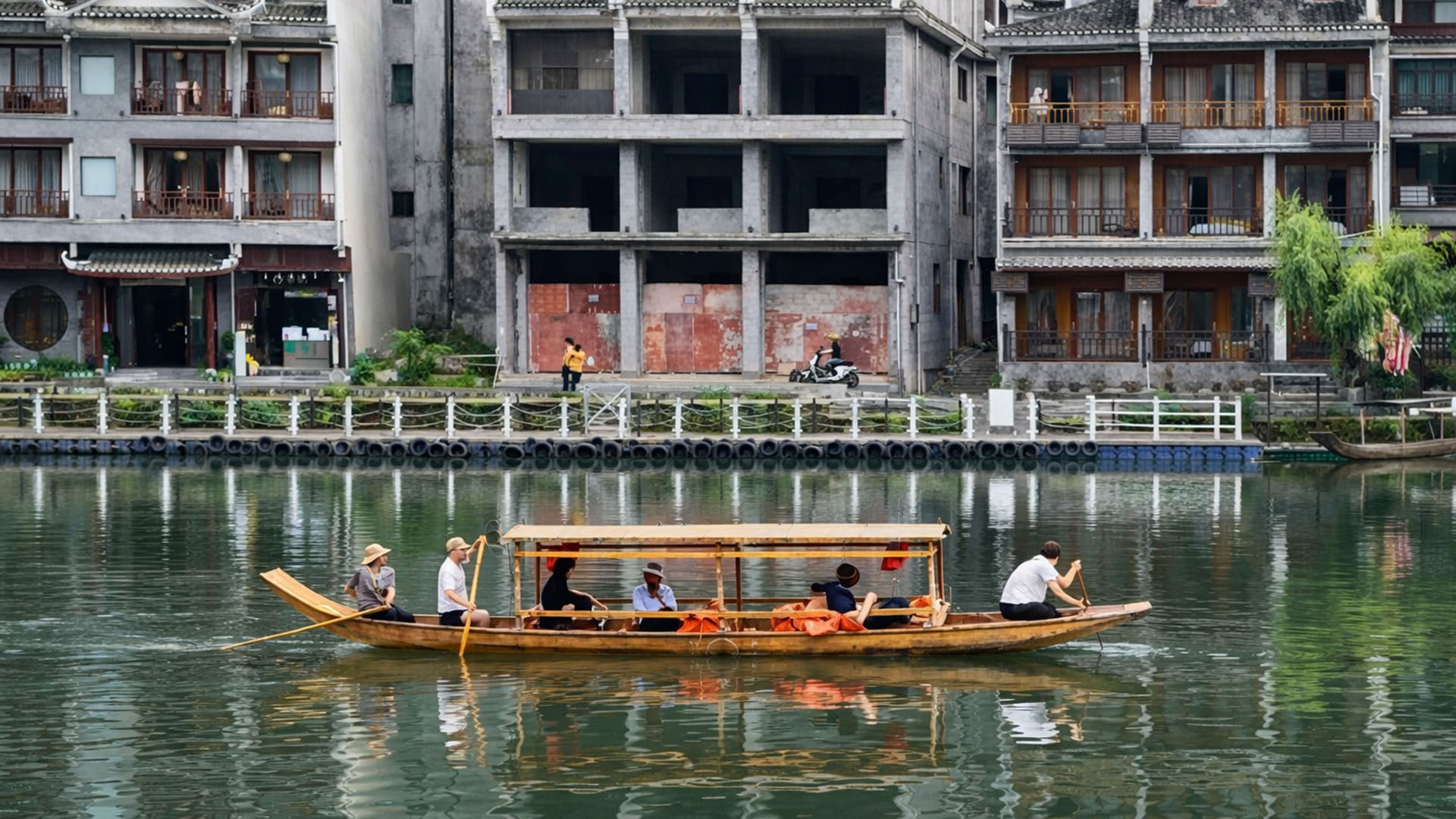 A wooden boat carries visitors across a quiet river in China