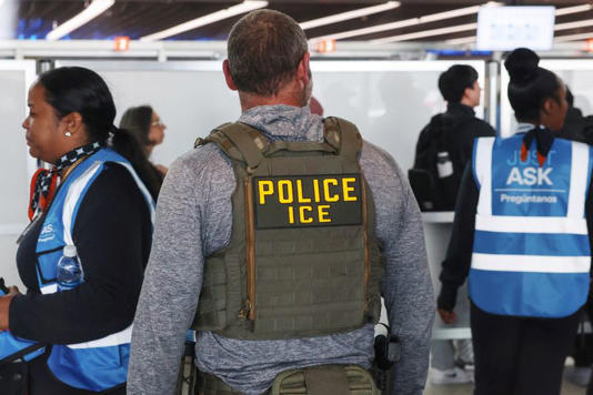 An Immigration and Customs Enforcement (ICE) agent stands while air travellers wait in TSA Security lines at John F. Kennedy International Airport, Queens, New York City, U.S., March 27, 2026. REUTERS/Shannon Stapleton