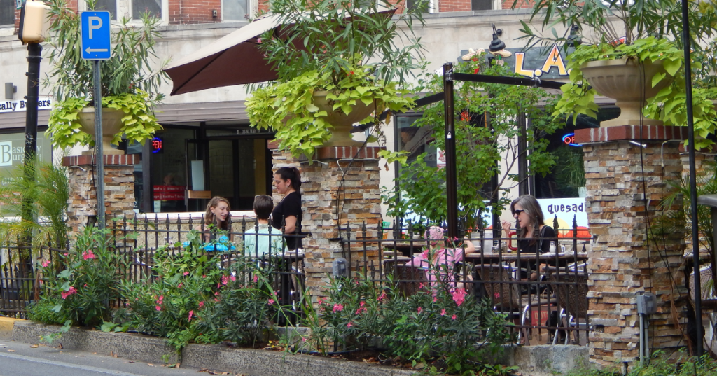 Diners enjoying an outdoor patio surrounded by greenery and stone pillars in Doylestown, Pennsylvania.