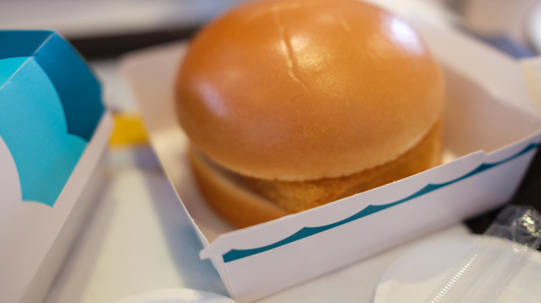 McDonald's Filet-O-Fish sandwich on a wooden table with a red carton of fries behind it