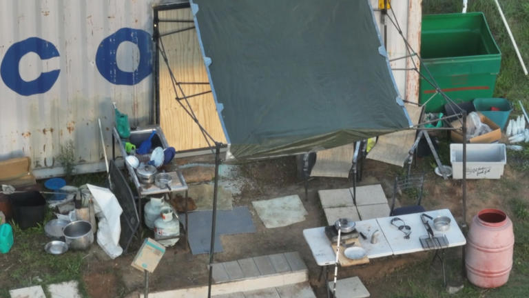 A cleaning station featuring a drying rack, several plates, pots and large bottle suggest Freeman may have been living on the property for a while.