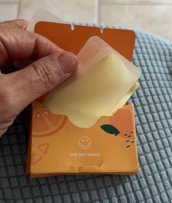 Hand holding a pack of soap sheets with a smiley face and