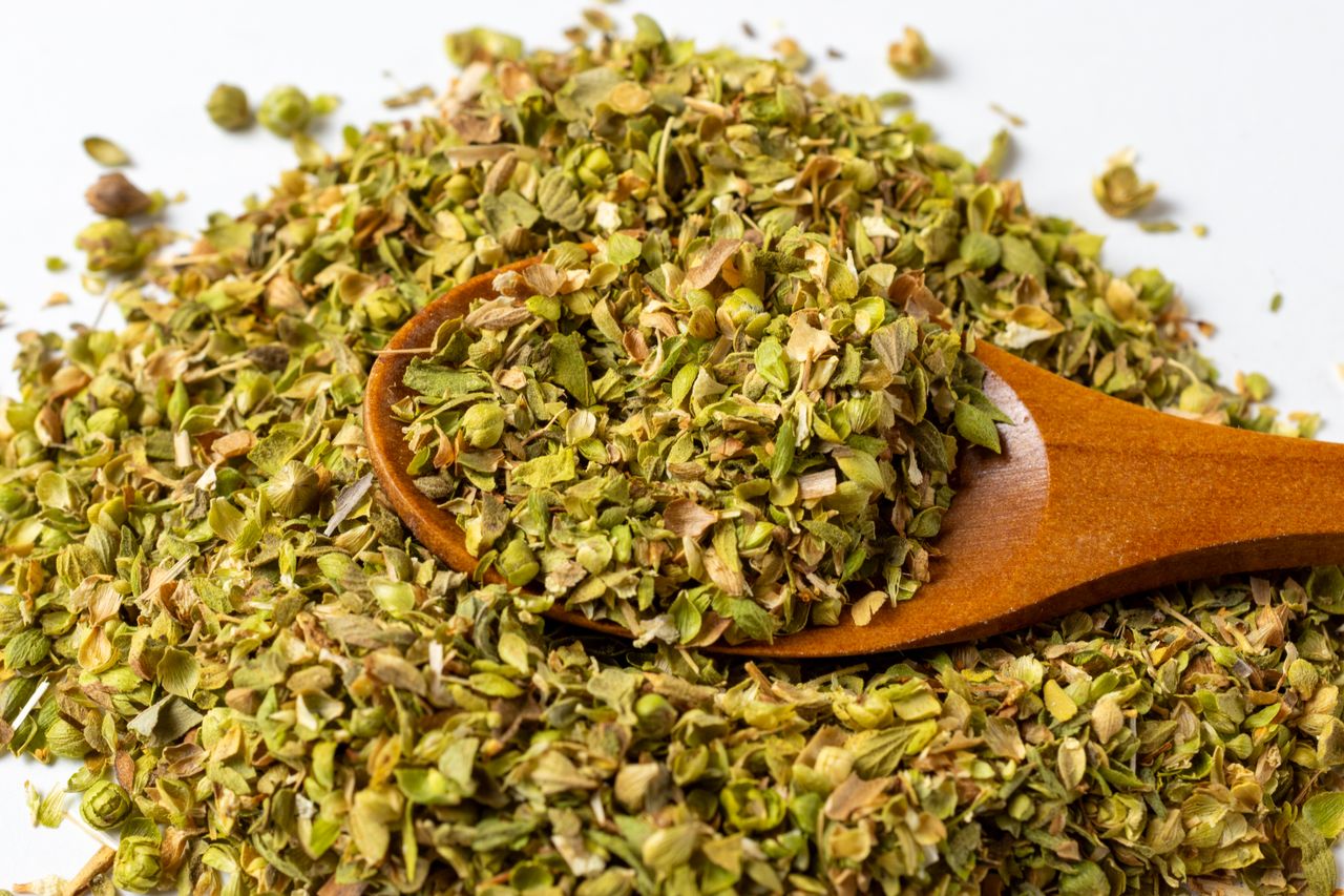 Dried herbs with a wooden spoon on a white background