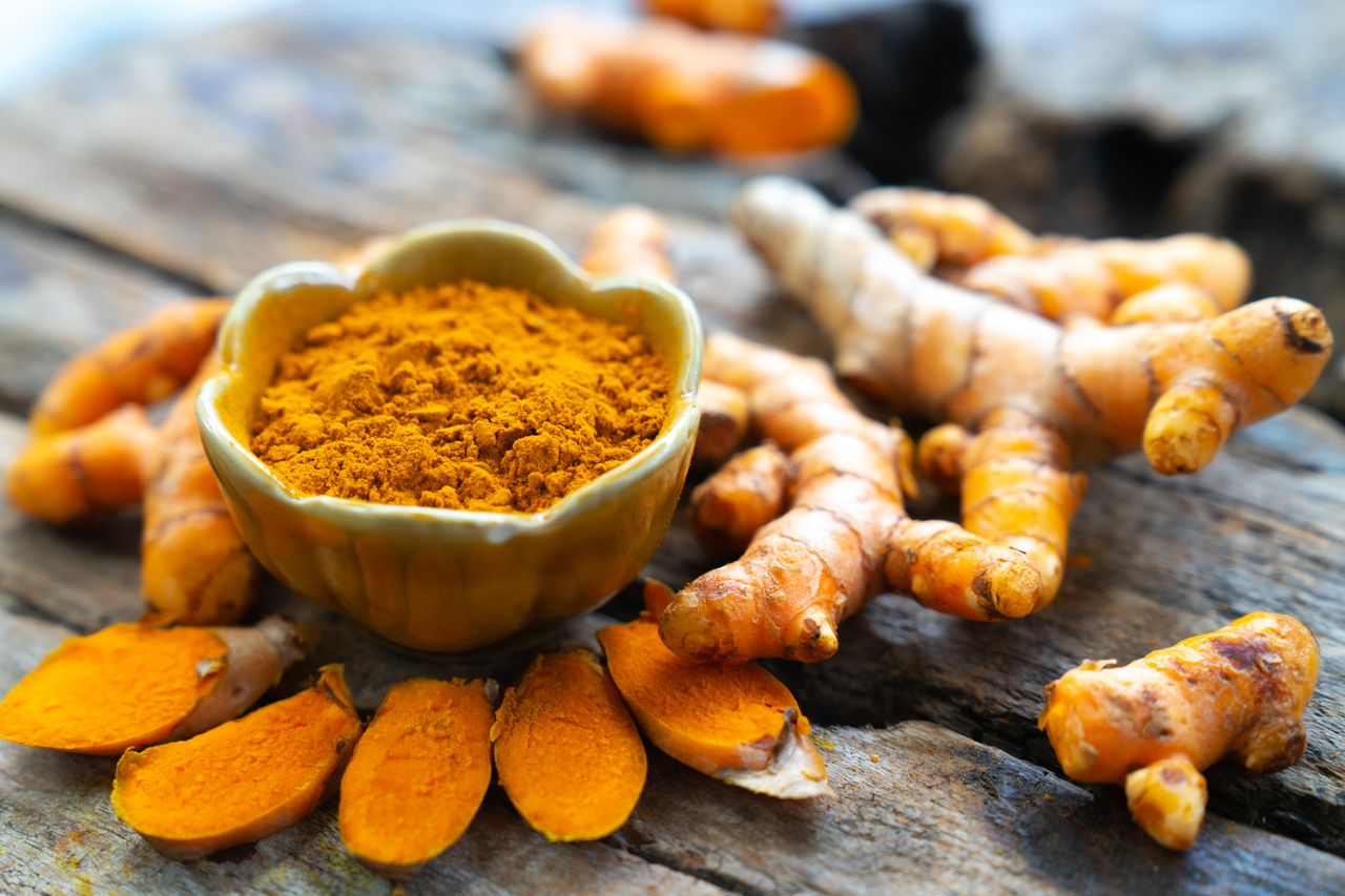 Turmeric root and powder on a wooden surface