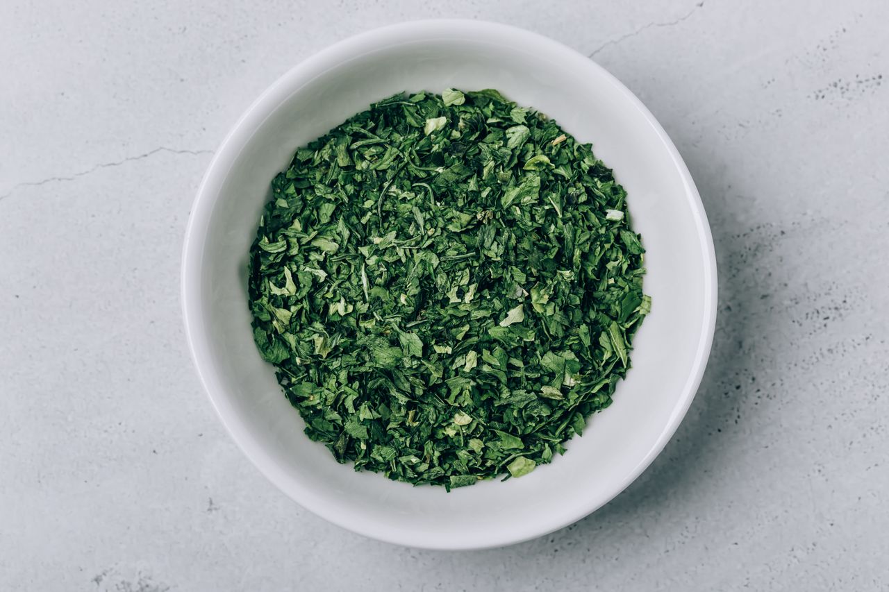 A bowl filled with dried leafy green herbs