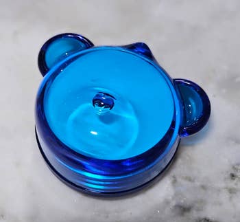 Glass bear-shaped ring holder on a marble surface