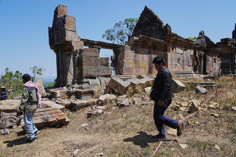 Cambodian police officers walk past a temple damaged during border clashes with Thailand, at Preah Vihear province, Cambodia, Saturday, March 14, 2026, (AP Photo/Heng Sinith)