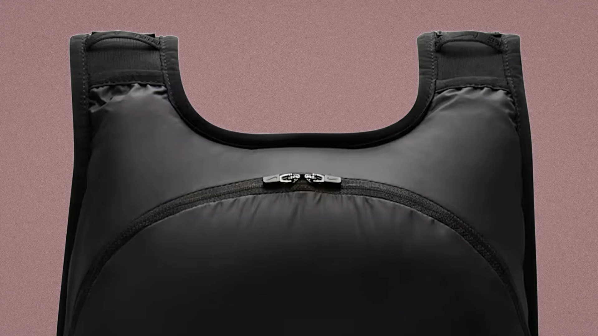 Black padded vest with a front zipper pocket and wide shoulder straps against a brown background.