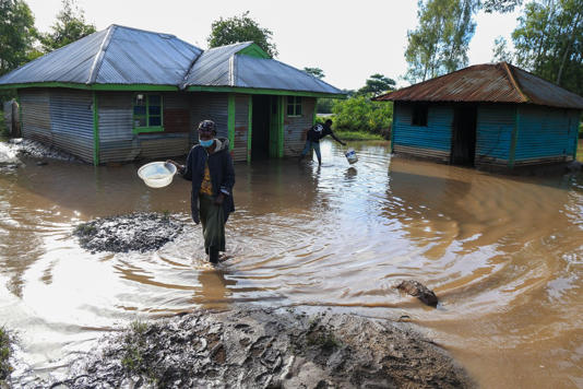 A woman walks through flood waters following heavy rains in Ahero, Western Kenya, Tuesday, March 24, 2026. (AP Photo/Andrew Kasuku)