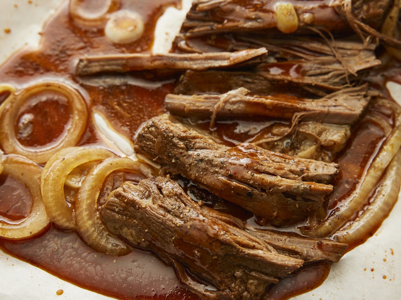 mid angle looking into sliced beef brisket with onions, soaking in all the juices