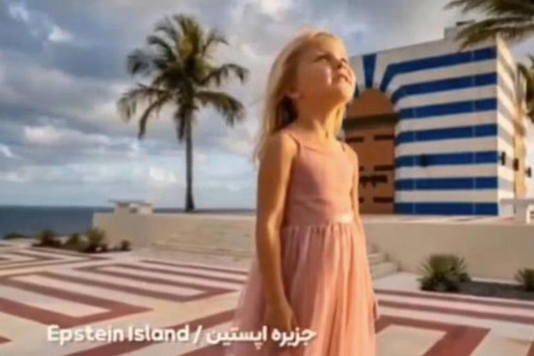 Una niña con un vestido rosa está de pie sobre un sendero embaldosado, mirando hacia arriba con un edificio de rayas azules y blancas, palmeras y una vista lejana del océano de fondo