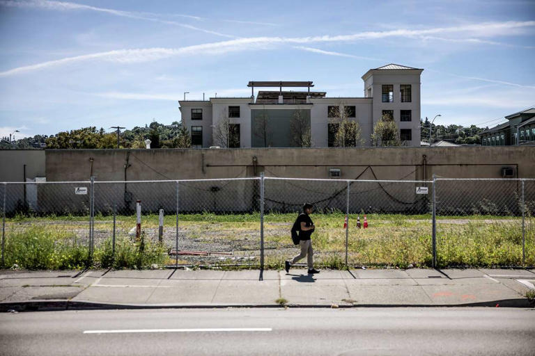 A pedestrian walks by an empty lot where the building at 703 Third St. once stood in San Rafael. The site is slated to be replaced with a new, higher tower. (Carlos Avila Gonzalez/S.F. Chronicle)