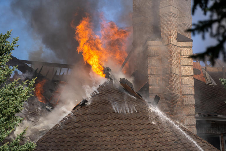 Firefighters battle house fire in Sandy, smoke and flames visible