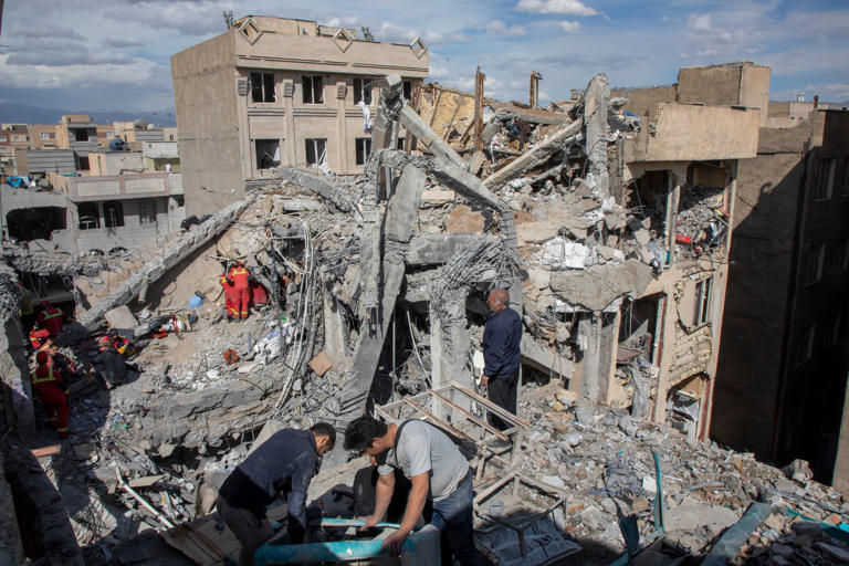 Residents and emergency workers sift through rubble of a residential building that was hit in an airstrike in the early hours of Friday in Tehran, Iran (Getty)