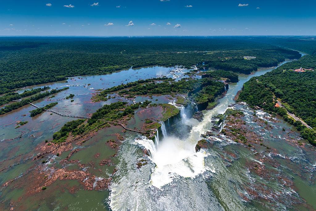 <p>One of the best ways to view the famous Iguazú Falls is by helicopter. It's located on the border between Brazil and Argentina and is thought to be one of the great wonders of nature. This area has the largest and longest waterfalls in the world with over 275 drops with the deepest being 269-feet long.</p> <p>When visitors fly over the falls they can get a bird's eye view of the iconic Devils' Throat canyon and the surrounding jungle. Some helicopter tours will stop near walkways where people can step right in front of the waterfalls.</p>