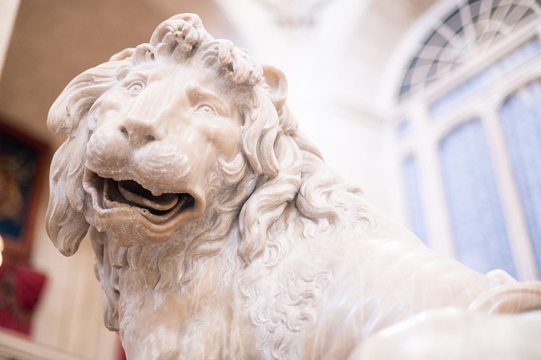 Two lions are positioned on the left and right sides of the first landing of the Grand Staircase inside the Royal Palace of Madrid. Artists Robert Michel and Felipe de Castro each created a lion. One looks up towards the ceiling and the other down at the stairs as guests enter the palace.