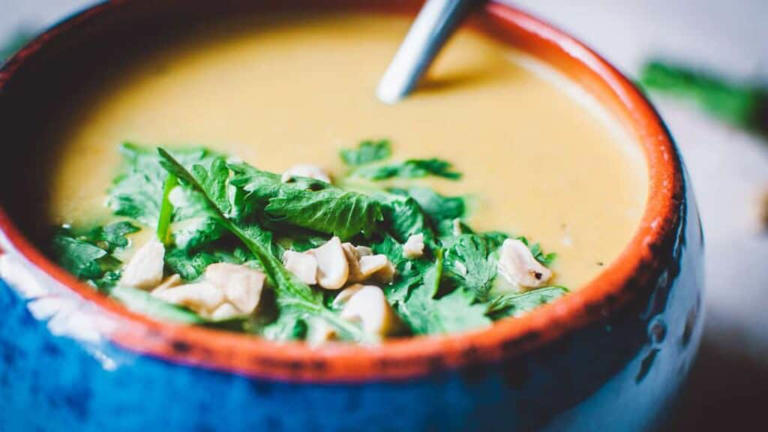 Close shot of a blue bowl of yellow soup.