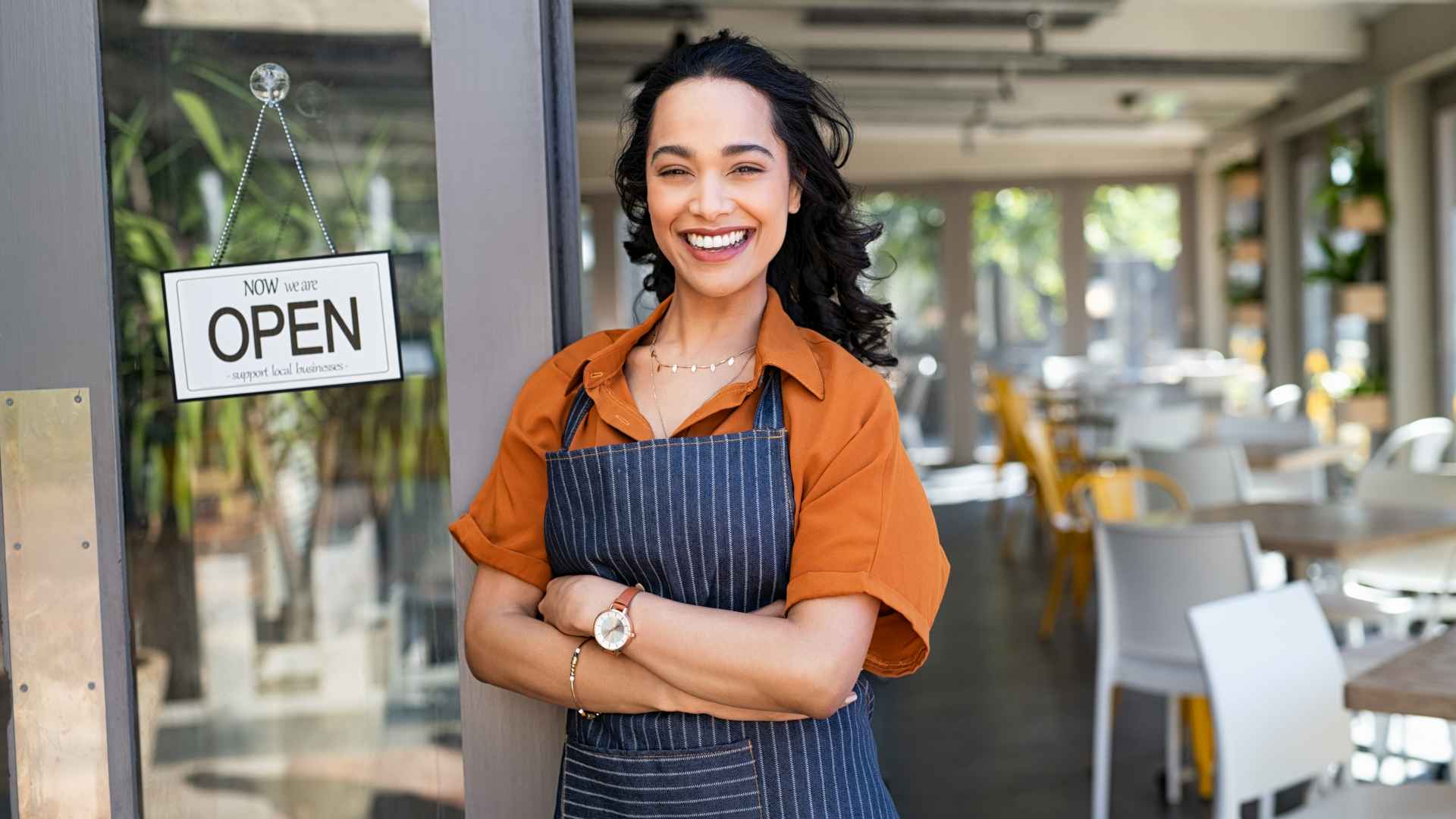 Successful small business owner standing at cafe entrance