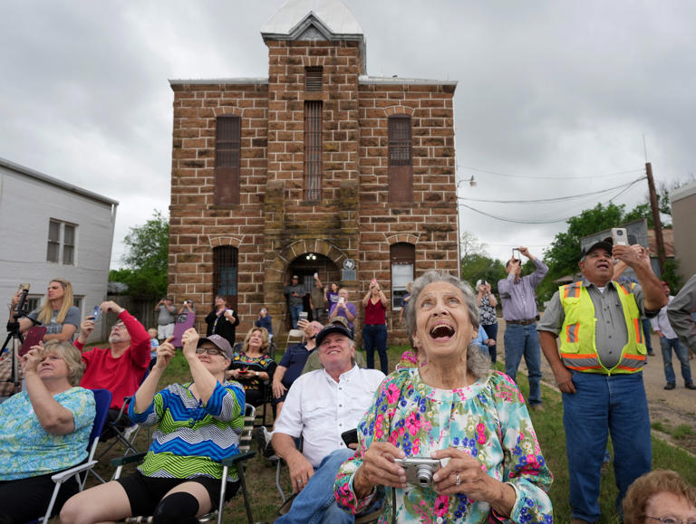 Fran Hoerster watches workers set a new crown on top of the Mason County Courthouse in Mason on Wednesday April 19, 2023. Residents lined the town square to watch workers secure the cupola to the courthouse that was heavily damaged in an arson fire in 2021.