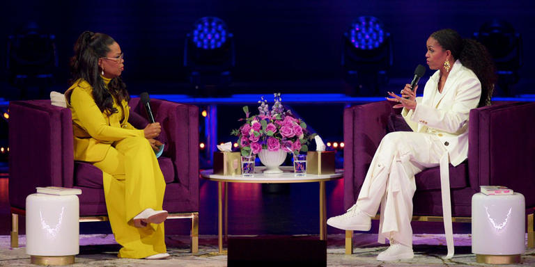 Michelle Obama and Oprah Winfrey are having a conversation on stage. 