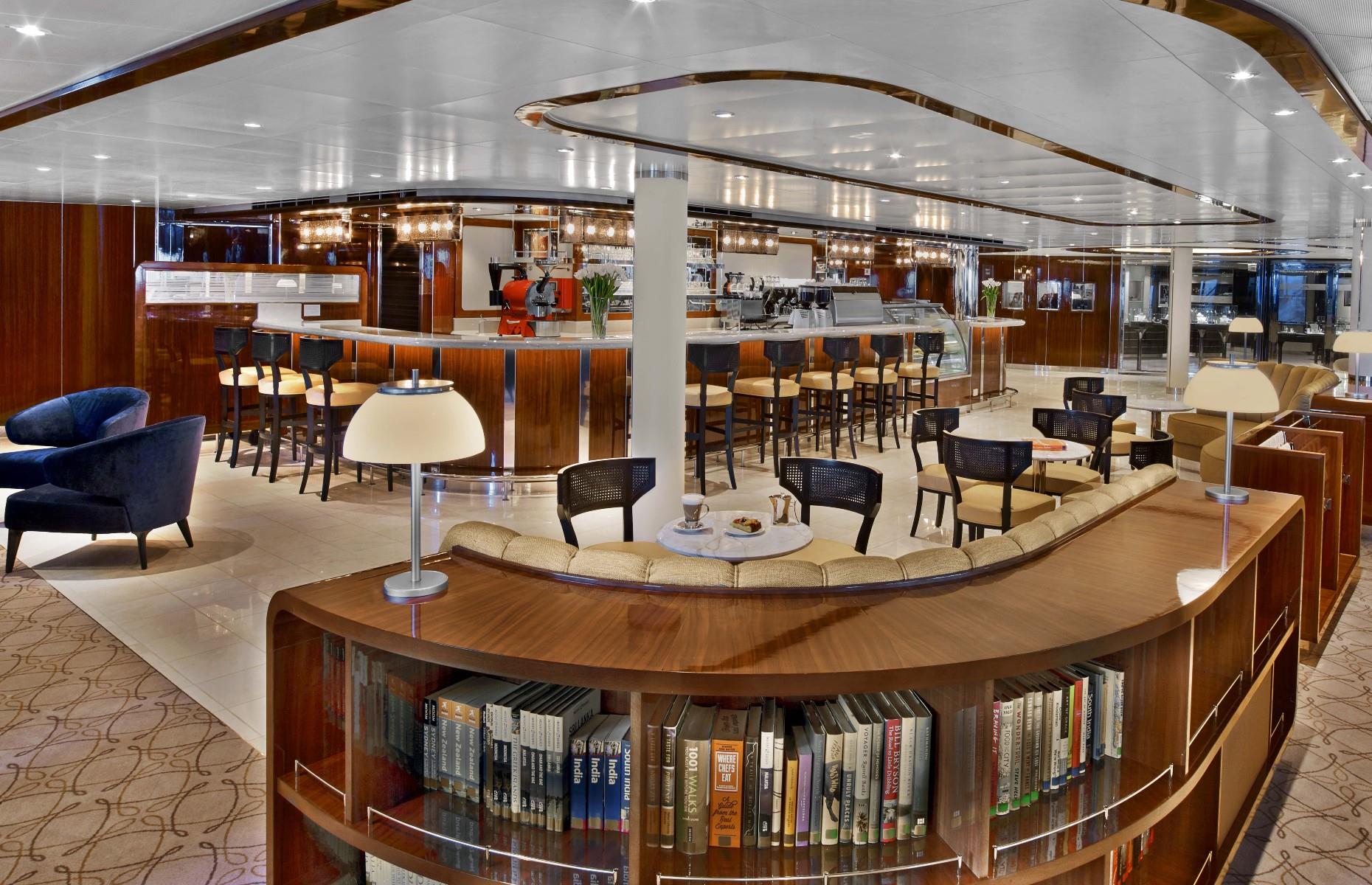 <p>Seabourn Square, designed to be an innovative concierge lounge, invites guests to access every shipboard service in a relaxed, living-room atmosphere. The Square's thoughtful layout includes a library, upscale shops, an outdoor terrace and a coffee bar, all arranged across a light-filled space with dark-wood accents, a subtle colour palette and striking blue velvet armchairs.</p>