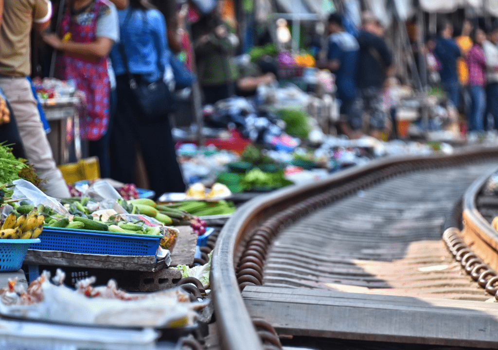 <p>If your career didn’t push you out of your comfort zone enough, a visit to the Maeklong Railway Market near Bangkok might. Every day locals set up their shops along more than 300 feet of an active railway.</p> <p>Trains arrive multiple times per day, causing the vendors to have to move their products and tents out of the way. It’s a thrill as a tourist to ride into the Maeklong Railway Market on the train and then walk back along the tracks. </p> <p>Just prepare to press yourself against the side of a building when a train passes!</p> <p>The Maeklong Railway Market is one of the most off-the-beaten-path bucket list suggestions on this list. You’ll need to be steady on your feet, for it’s easy to trip on the stones when walking along the train tracks.</p>