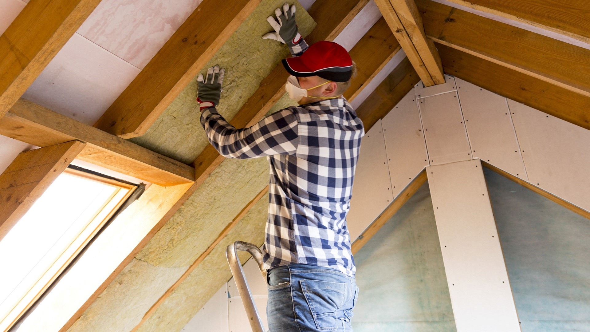 masked man installs insulation attic_iStock-873936662