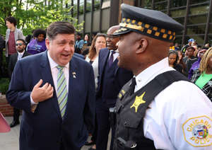 Gov. J.B. Pritzker talks with Chicago police Cmdr. Andre Parham, 15th District, before a pre-inauguration event for Mayor-elect Brandon Johnson outside Michele Clark Magnet High School on May 15, 2023.