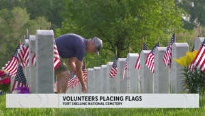 Volunteers place flags at Ft. Snelling gravestones for Memorial Day