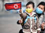 A woman and her grandson wave North Korea's national flag in Pyongyang on March 8, 2023. KIM WON JIN/AFP via Getty Images