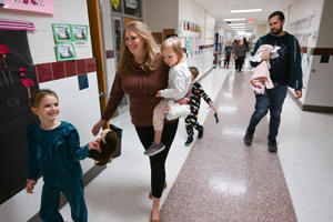 Aimee walks ahead of Christina, carrying Aurelia, while followed by Aaron during a reading event at Round Hill Elementary.