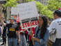 People carry signs in support of the Writers Guild of America outside the NBCUniversal offices in New York on May 23.